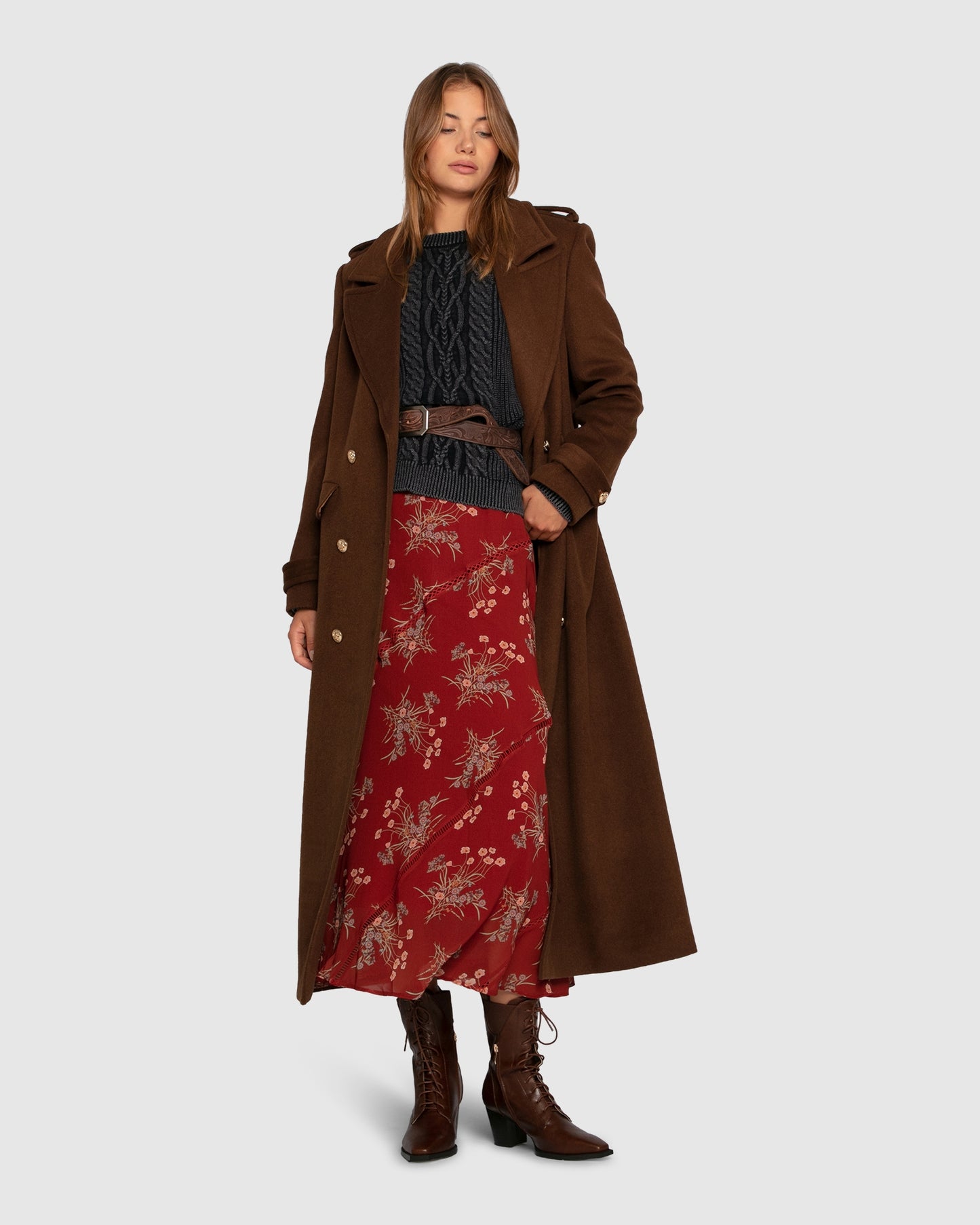 Women's cable knit sweater with garment-dyed finish and relaxed fit in navy styled with long brown coat and floral maxi