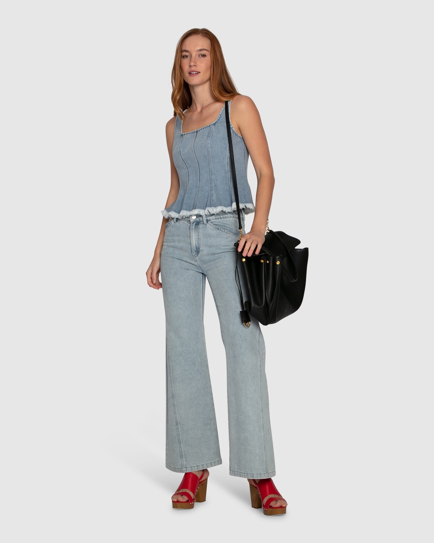 Woman wearing Belle & Bloom Hold Me Brave Denim Top, featuring vertical seams, square neck and fringed hemline