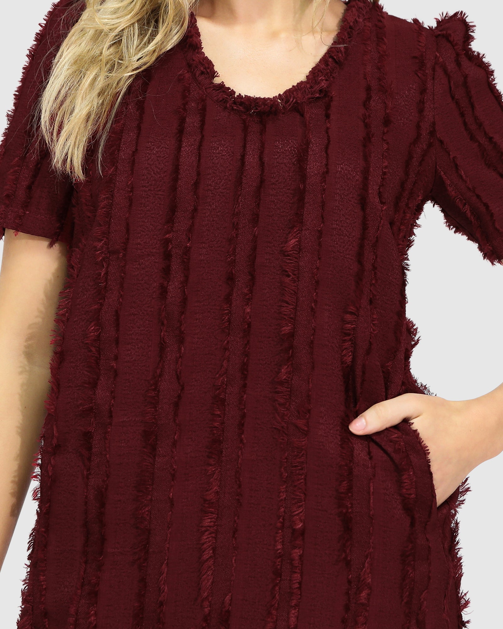 Close-up of Belle & Bloom's burgundy Solana Boho Fringe Mini Shift Dress featuring a textured fabric and frayed V-neckline.