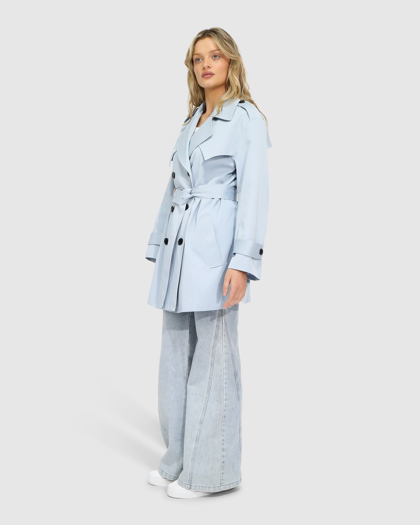 Side view of woman wearing the Whispers of Verona Trench Coat in sky blue, highlighting the belted waist, structured silhouette, and soft drape – Belle and Bloom trench coat.