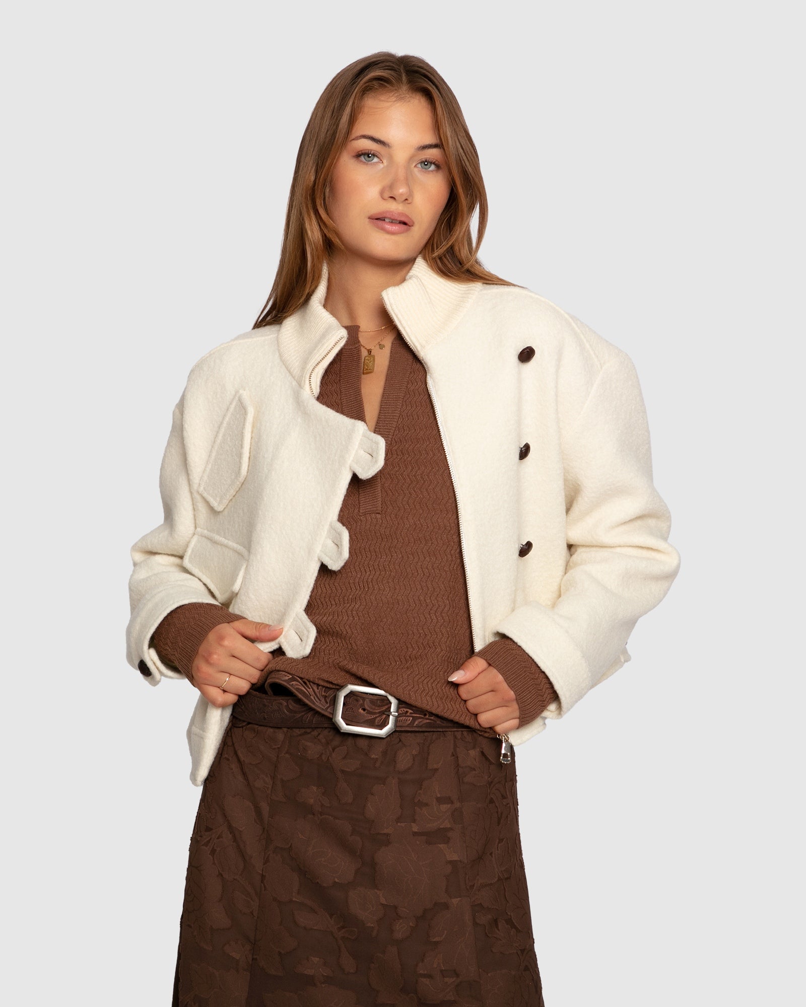 Textured knit top detailed view chocolate with brown skirt, cream coat and brown belt

