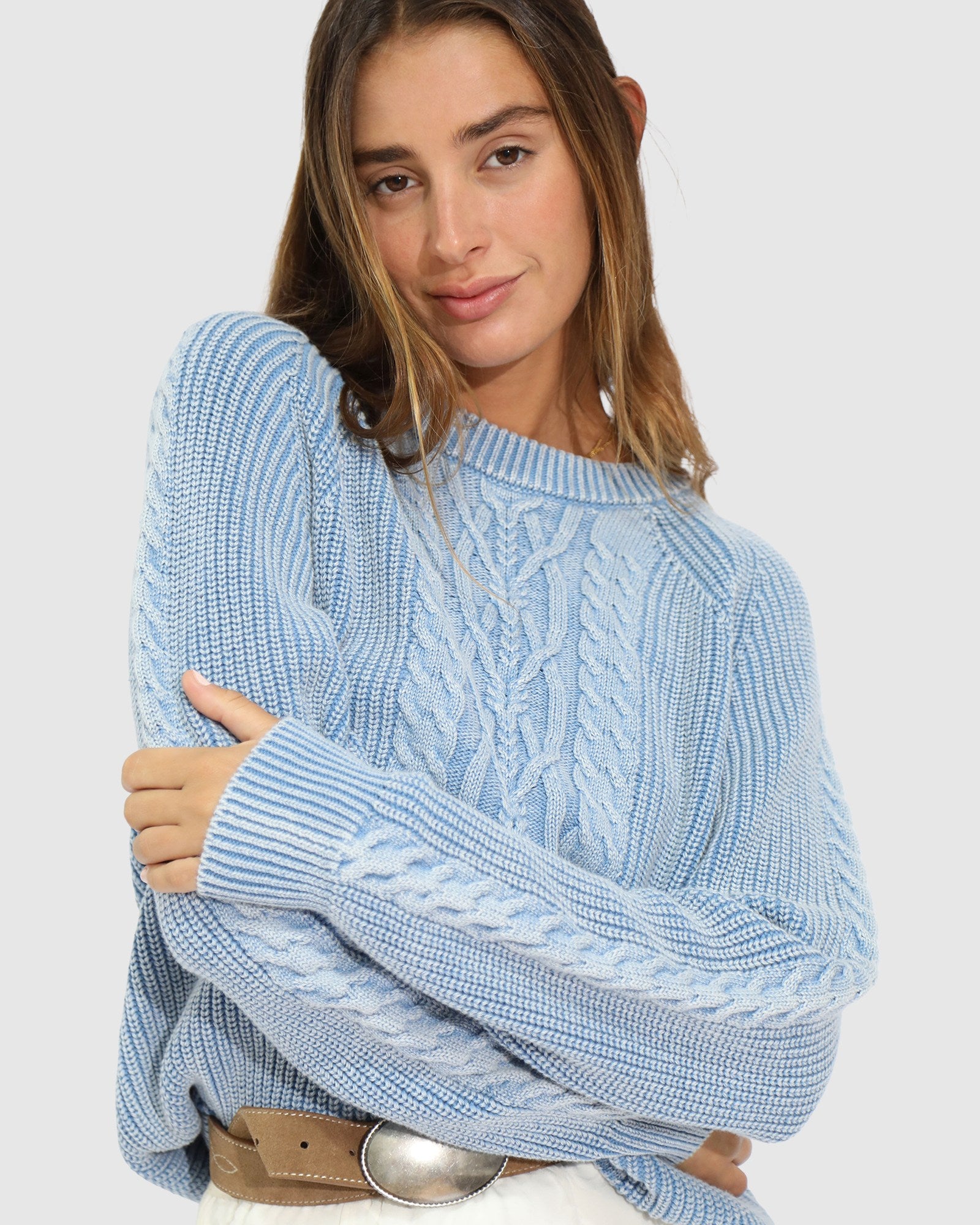 Woman wearing light blue cable knit sweater 
