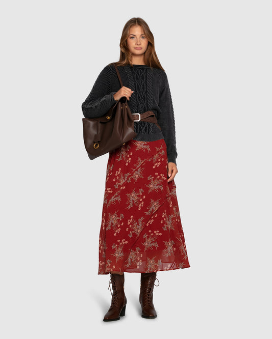 Woman wearing navy cable knit sweater  with floral dress and boots