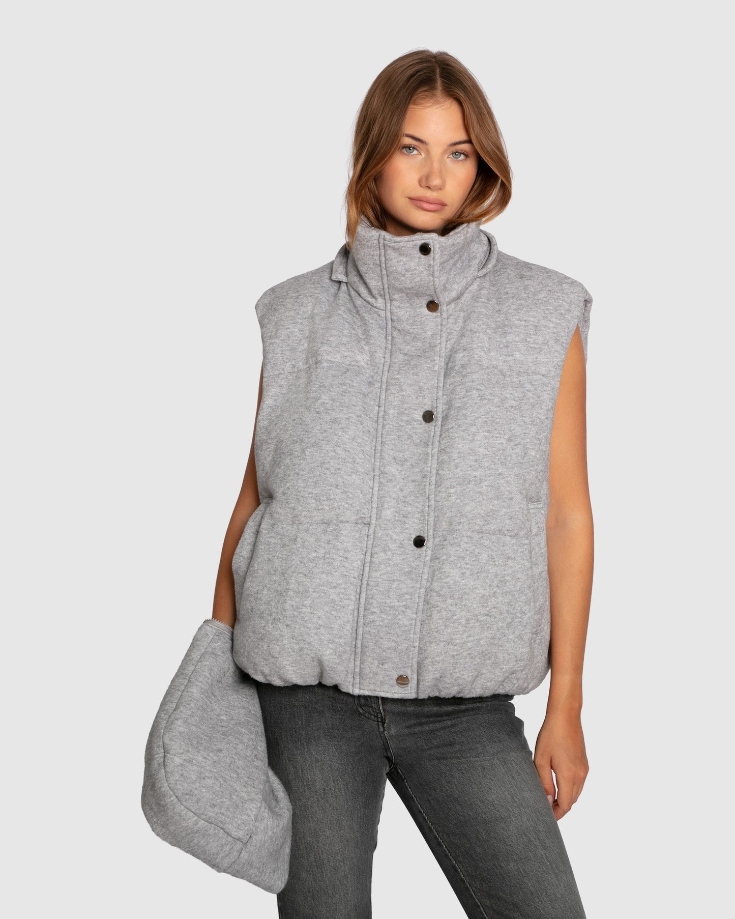 Woman wearing grey melange puffer vest showing detachable hood
