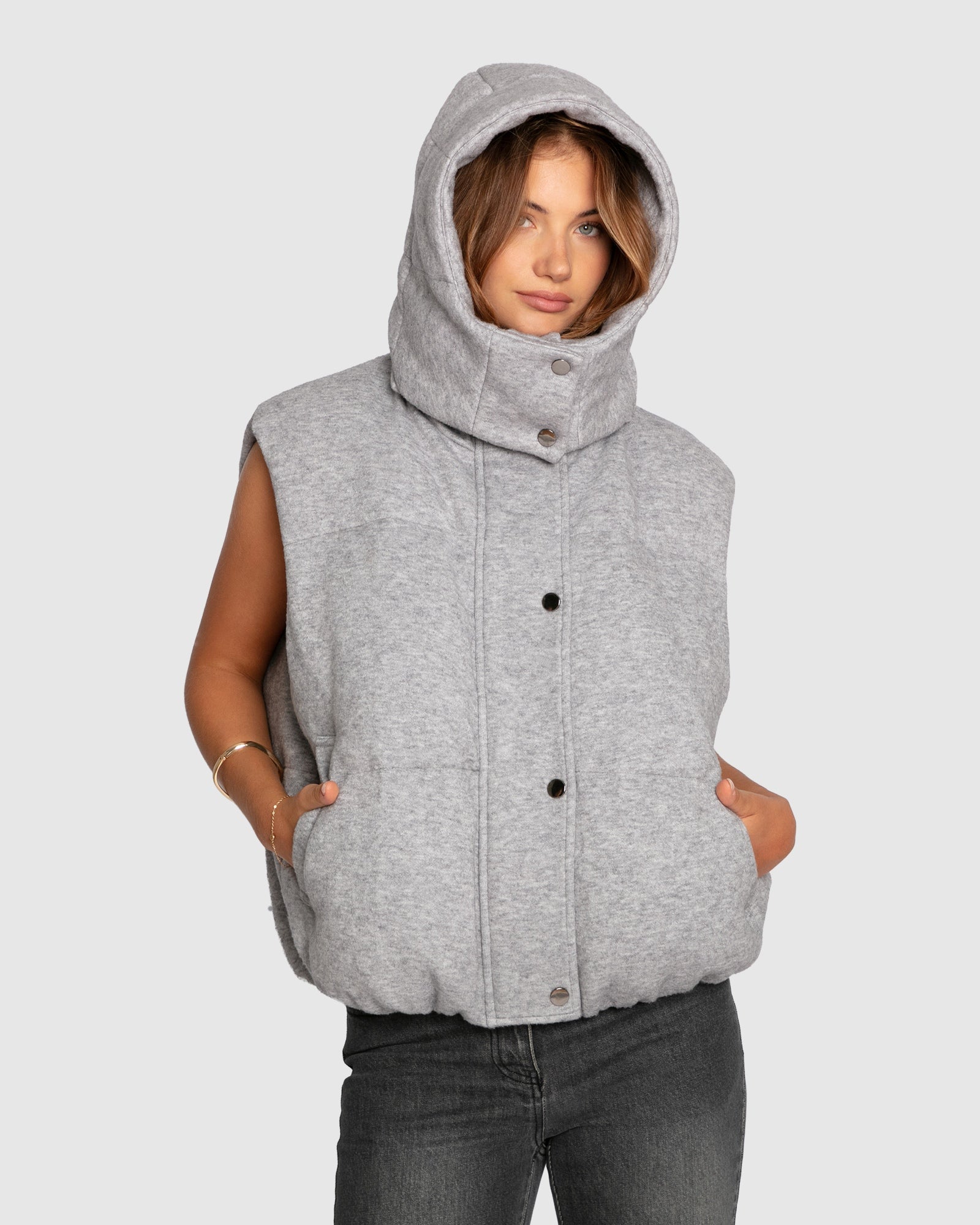 Woman wearing grey melange puffer vest with hood up
