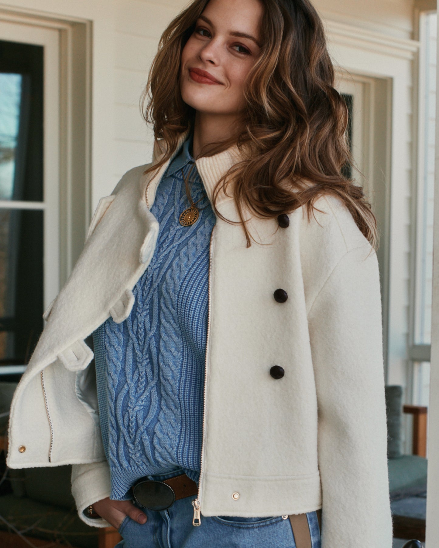 Woman wearing light blue cable knit sweater with cream wool coat