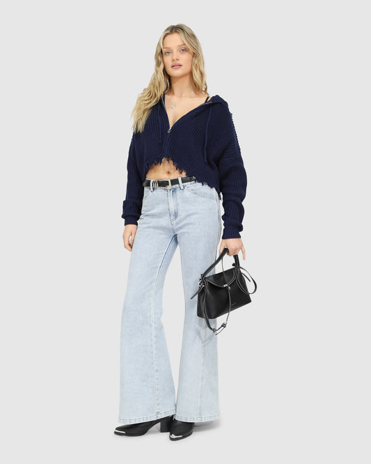 Woman wearing the Another Love Fringe Knit Zip Cardigan in navy, featuring chunky knit texture, zip front, drawstring hood, and fringed cropped hem – Belle and Bloom knitwear.
