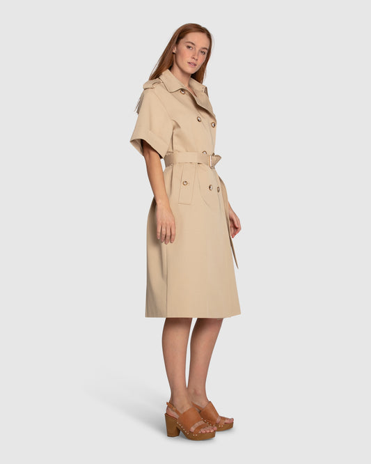 Side angle of Belle & Bloom Dust & Daring Short Sleeve Trench Style Dress in beige, showing short sleeves, belted waist and structured trench silhouette.