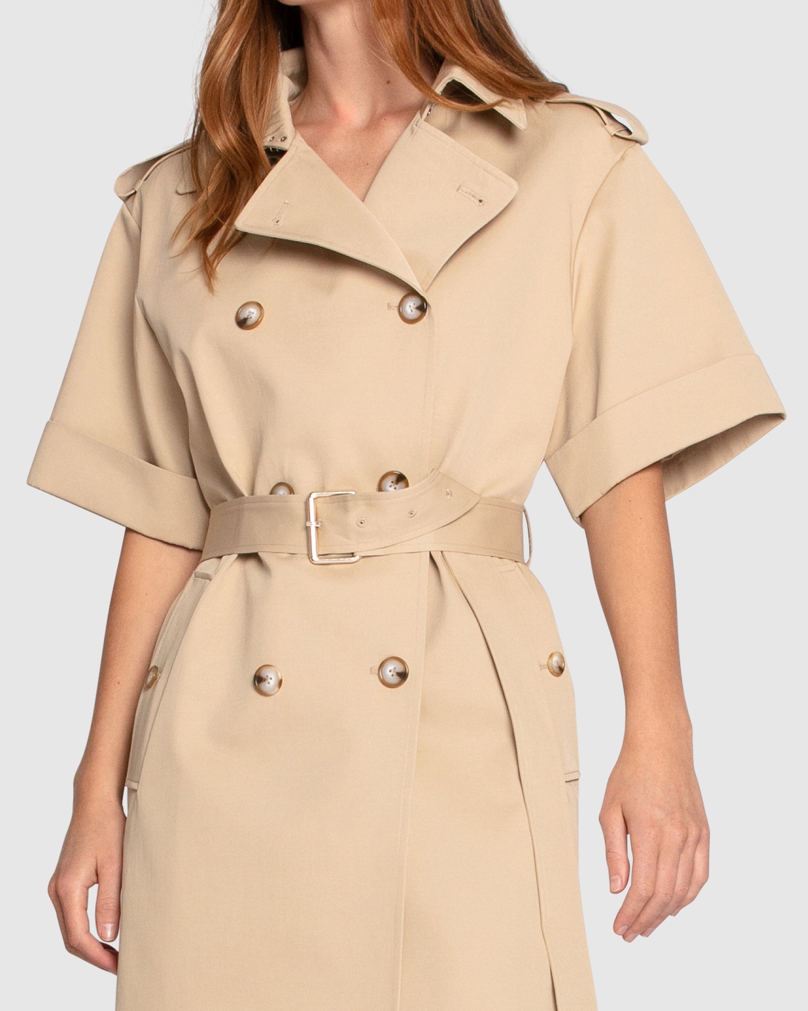 Close-up of Belle & Bloom Dust & Daring Short Sleeve Trench Style Dress in beige, highlighting double-breasted buttons, wide lapel collar and waist belt.