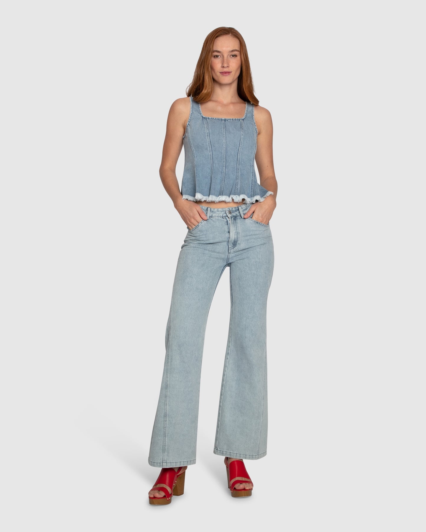 Woman wearing Belle & Bloom Hold Me Brave Denim Top, featuring vertical seams, square neck and fringed hemline