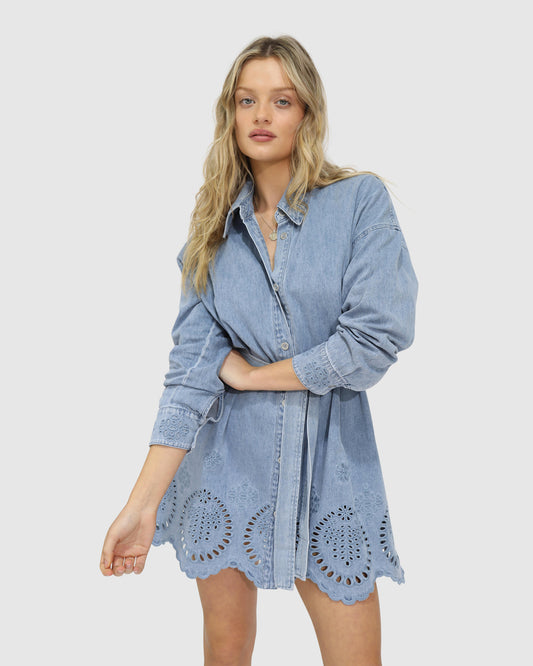 Model wearing the Sunday Somewhere Denim Broderie Shirt Mini Dress by Belle & Bloom – puff sleeves, button-down front, broderie anglaise detail
