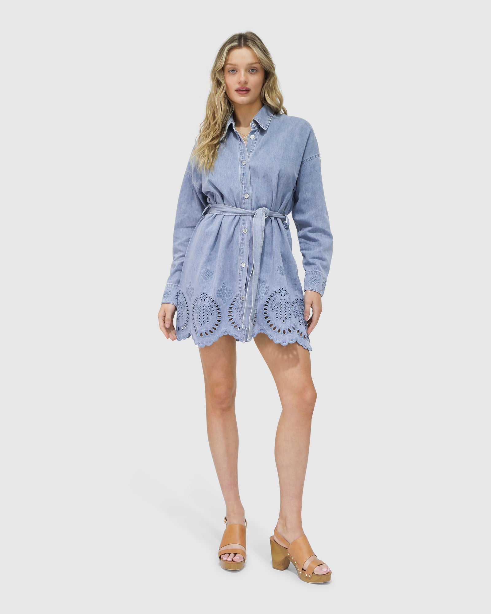 Model wearing the Sunday Somewhere Denim Broderie Shirt Mini Dress by Belle & Bloom – puff sleeves, button-down front, broderie anglaise detail